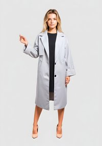 Abrigo tipo gabardina gris claro con solapas anchas, mangas largas y dos botones grandes. Presenta un corte recto y llega por debajo de la rodilla. Textura suave.