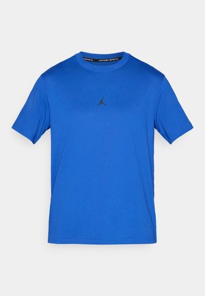 Zila īsām piedurknēm T-kreklu, kas izgatavots no viegla auduma; uz krūtīm redzams melns Jordan logotips. Apaļa kakla izgriezums un gluda tekstūra.