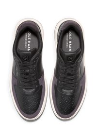 Černé kožené a šedé semišové tenisky s perforovanou špičkou, černými tkaničkami, zaoblenou bílou podrážkou a logem na jazyku.