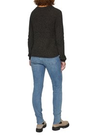 Donkerbruin gestructureerd truitje met lange mouwen, ronde hals, gecombineerd met lichtblauwe slim-fit jeans en lichtkleurige enkellaarsjes met een dikke zool.