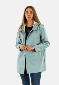 Chaqueta impermeable de color azul claro con capucha, botones a presión y bolsillos laterales. Presenta un cuello interior blanco en contraste y un corte relajado.