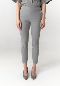 Grijze slim-fit broek met een gladde textuur, taps toelopende pijpen en enkellengte, gecombineerd met puntige grijze hakken.