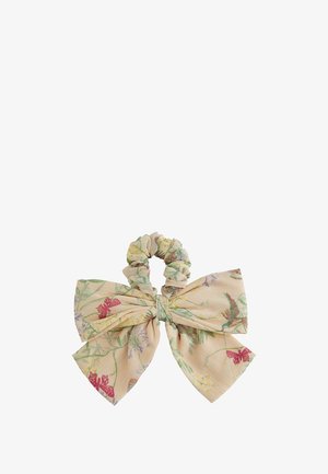 Chouchou avec un grand nœud doux en tissu beige imprimé de vignes vertes, de papillons rouges et de fleurs discrètes violettes et jaunes.