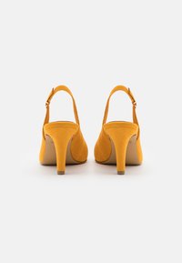 Žluté semišové lodičky na vysokém podpatku s kulatou špičkou, tenkým podpatkem a nastavitelným popruhem kolem kotníku. Hladká textura s minimálními detaily.