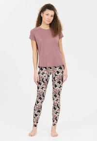 Haut violet à manches courtes associé à un legging ajusté avec un motif floral en rose, crème et noir sur un fond clair.