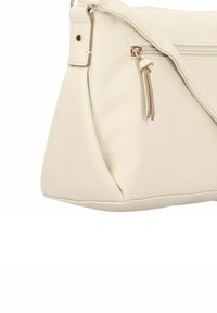 Bolso de piel color crema con una superficie texturizada, forma angular y un bolsillo con cremallera que cuenta con un pequeño tirador de cuero.