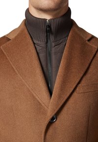 Brązowy płaszcz z mieszanki wełny z wysokim prążkowanym kołnierzem, z suwakiem z przodu i gładkim podszewką. Posiada kieszeń na piersi i detale z guzikami.
