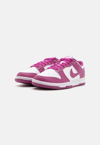 Nike tornacipők rózsaszín és fehér bőrdesignnal, perforált orral, rózsaszín fűzőkkel és texturált gumitalpával.
