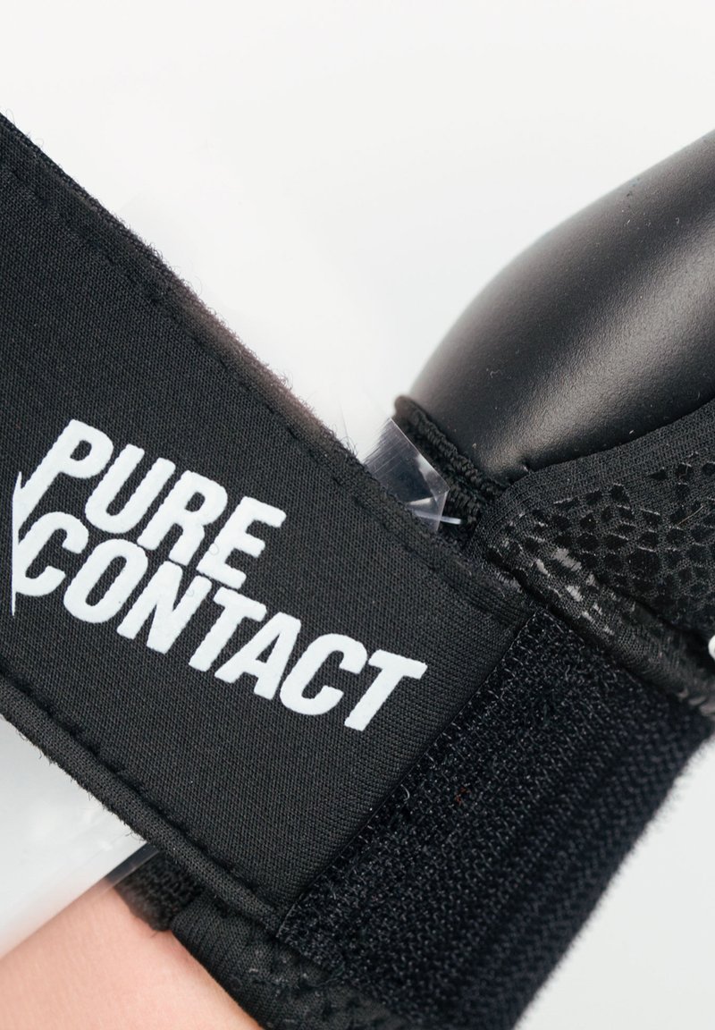 Schwarzer athletischer Handgelenkschutz mit weißer Beschriftung "PURE CONTACT", verfügt über eine glatte Textur, einen verstellbaren Riemen und schützende Polsterung.