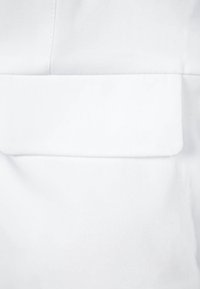 Vitt tyg med en slät textur som har en stor, platt ficka i mitten, sydda kanter och ett subtilt diagonalt vävmönster.