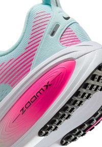 Gros plan du talon d’une chaussure de sport bleu clair et rose avec une semelle blanche, une bande de roulement noire et un marquage « zoomx » sur le panneau de soutien de la semelle intermédiaire rose.