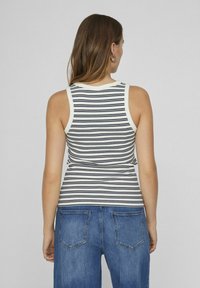Stripet tanktopp i marineblått og hvitt, ribbestruktur, tettsittende design med rund halsutskjæring og brede skulderstropper, kombinert med blå jeans.