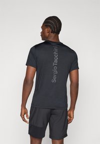 Μαύρο αθλητικό τ-shirt κοντομάνικο με μια διακριτική λογότυπο "Sergio Tacchini" κάθετα στη πλάτη. Φοριέται με μαύρη βερμούδα.