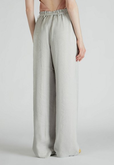 Jasnoszare szerokie spodnie z elastycznym paskiem w talii, wykonane z teksturowanej tkaniny. Brak widocznych kieszeni lub ozdób.