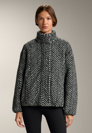 Čierna a biela sako so vzorom rybej kosti, vyrobené z plyšového materiálu, s vysokým golierom a voľným strihom. Má dlhé rukávy a bočné vrecká.