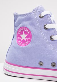 Fioletowe płótno wysokie trampki z białymi sznurowadłami, różowymi akcentami, okrągłym logo oraz metalowymi oczkami. Gumowa podeszwa z kontrastowym wykończeniem.