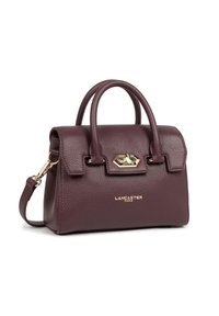 Borsa a mano in pelle viola scuro e texture con doppi manici, chiusura a scatto oro, tracolla rimovibile e logo "Lancaster Paris" sul fronte.
