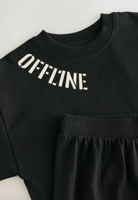 Sort sweatshirt med ordet "OFFLINE" i hvide blokbogstaver tværs over brystet. Lavet af bomuldsmateriale med ribbet halsudskæring og manchetter.