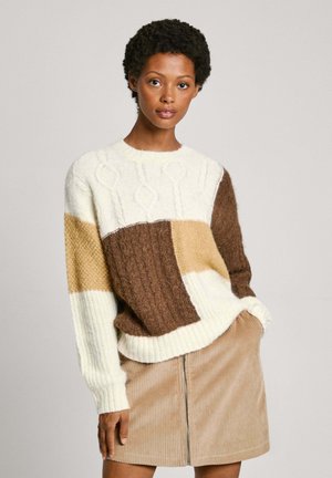 Maglione lavorato a maglia caratterizzato da un mix di patch color crema, marrone e beige; modelli testurizzati con scollo rotondo e polsini a costine. Abbinato a una gonna in velluto a coste.