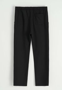 Pantalons noirs à taille élastique avec une poche patch au dos, jambes droites et sans fermetures visibles, présentés sur un fond clair.