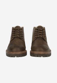 Chaussures en cuir marron avec bouts ronds, design à lacets et semelles en caoutchouc texturées. Coutures remarquables et accents marron clair contrastants.