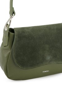 Green leather handbag featuring a textured, pebbled exterior and a soft suede flap. Accented with yellow stitching and a silver clasp.