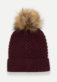 Burgundijas adīta cepure ar strukturētu dimanta rakstu un garu ribotu mali, rotāta ar pūkainu gaiši brūnu mākslīgā kažokādu pom-pom.