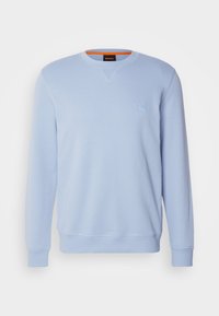 Sweat-shirt bleu clair à manches longues et col rond, avec poignets et ourlet côtelés, orné d'un petit patch carré avec logo sur la poitrine.