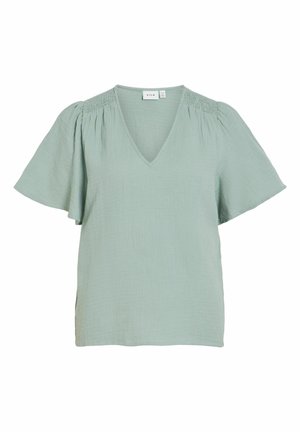 Blouse vert clair à manches courtes avec un col en V et un détail froncé sur les épaules, coupe ample, matière légère et texturée.