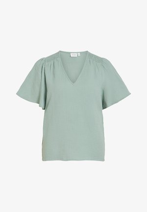 Blouse vert clair à manches courtes avec un col en V et un détail froncé sur les épaules, coupe ample, matière légère et texturée.