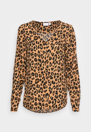 Leopards nēdas blūze oranžos un melnos toņos. Tam ir V veida dekoltē, garas piedurknes un brīva piegriezuma ar izliekumu apakšmalā.