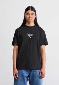 Sort bomulds T-shirt med rund hals og korte ærmer. Hvid tekst medfølger "PORSCHE LEAGUE TURBO CLUB" med et logo nedenfor.
