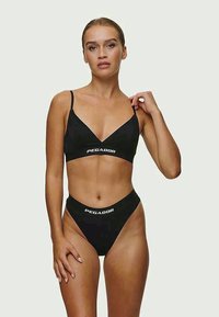Black swimwear set featuring a bralette top with adjustable straps and low-rise thong bottoms. Notable "PEGADOR" logo in white on both pieces.
