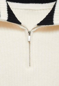 Cream-colored half-zip pullover with a black ribbed collar. Features a metallic zipper and textured fabric with vertical stripes.