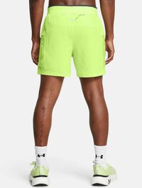 Pantalones cortos deportivos de color verde neón con cintura ajustable, que cuentan con bolsillos laterales y una textura suave y ligera. Combinados con calcetas y zapatos blancos.