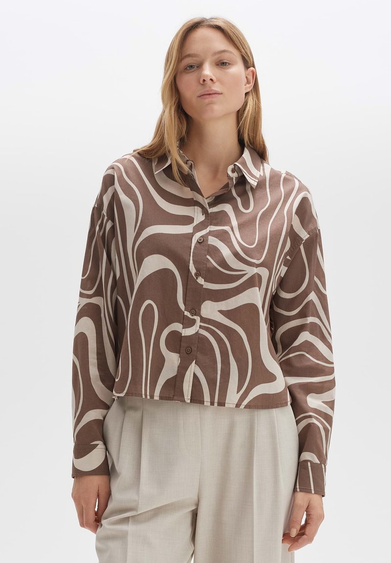 Brown and cream button-up shirt with abstract swirl pattern, lightweight fabric, cropped design, and pointed collar. Paired with light beige trousers.