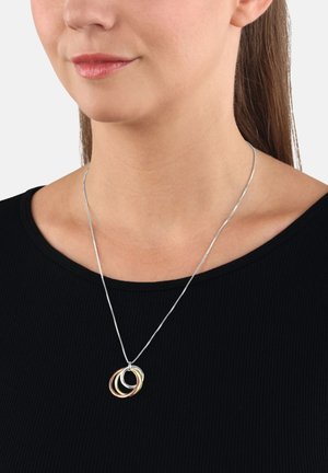 Collana in argento con tre anelli intrecciati in oro, argento e oro rosa. Il pendente riposa su una maglietta nera a coste.