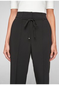 Zwarte broek van gestructureerde stof, met een elastische tailleband, zijzakken en een getailleerde pasvorm met voorvouwen.
