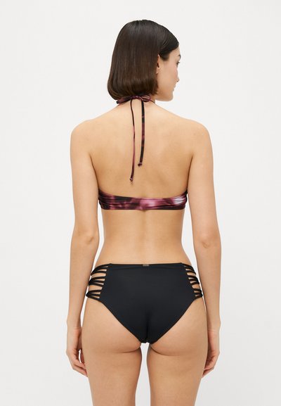 Bikini-Set mit einem pinken und schwarzen Oberteil mit Trägern zum Hineinbinden und hochgeschnittenen schwarzen Unterteilen mit seitlichen Ausschnitten.