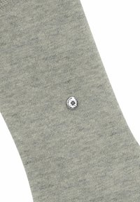Graue Baumwollsocke mit einem strukturierten Muster und einem runden Logo-Patch mit floralem Emblem nahe dem oberen Rand. Einfaches und funktionales Design.