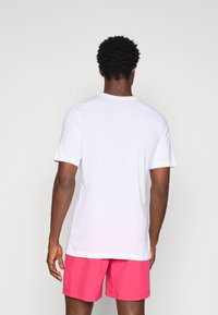 White short-sleeve t-shirt with a round neck, paired with pink shorts. The fabric appears smooth with no visible patterns or textures.