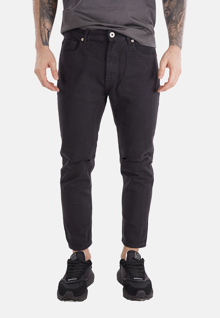 Jeans neri a gamba tapered con vestibilità slim, caratterizzati da chiusura frontale con bottone, cinque tasche e dettagli strappati sulle ginocchia.