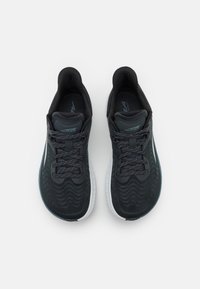 Scarpe da atletica nere con una parte superiore testurizzata, lacci intrecciati e suola bianca. Il design presenta sottili motivi a onda e branding.
