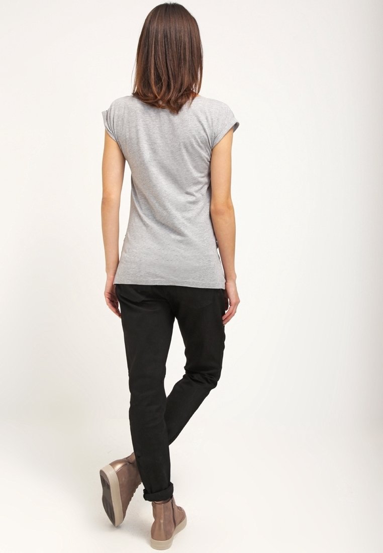 Camiseta gris de manga corta, pantalones negros ajustados y botas de tobillo marrones. Textura suave con mangas enrolladas, vista desde la parte de atrás.