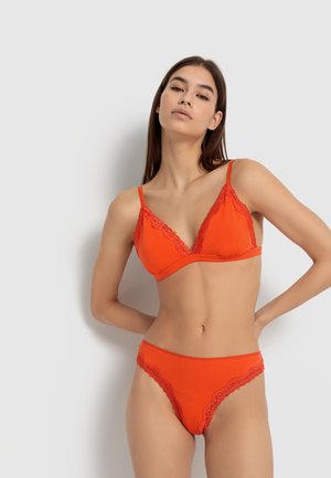 Rotes Dessous-Set mit einem dreieckigen BH und passenden Panties mit Spitzenbesatz, gleitendem Stoff und verstellbaren Trägern.