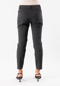 Pantaloni grigi su misura con una vestibilità slim, caratterizzati da una superficie liscia, passanti per la cintura e tasche laterali. L'orlo è accorciato appena sopra la caviglia.