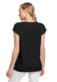 Sort T-shirt med korte ærmer, løs pasform, rund hals, blødt stof og oprullede ærmer, set fra ryggen.