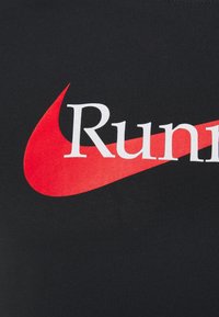 Svart bomulls t-shirt med en stor röd Nike swoosh och ordet "Run" i vit typografi över bröstet. Slät textur.