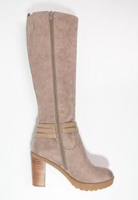 Botas de ante taupe hasta la rodilla con cremallera lateral, acabado texturizado y tacón de madera apilado. Presentan un acento de doble tira cerca del tobillo.