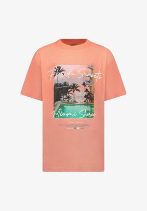 Perzikkleurig T-shirt met korte mouwen en een bedrukte afbeelding van palmbomen en een zwembad. Tekst bevat "Florida Sunsets" en "Miami Shores".
